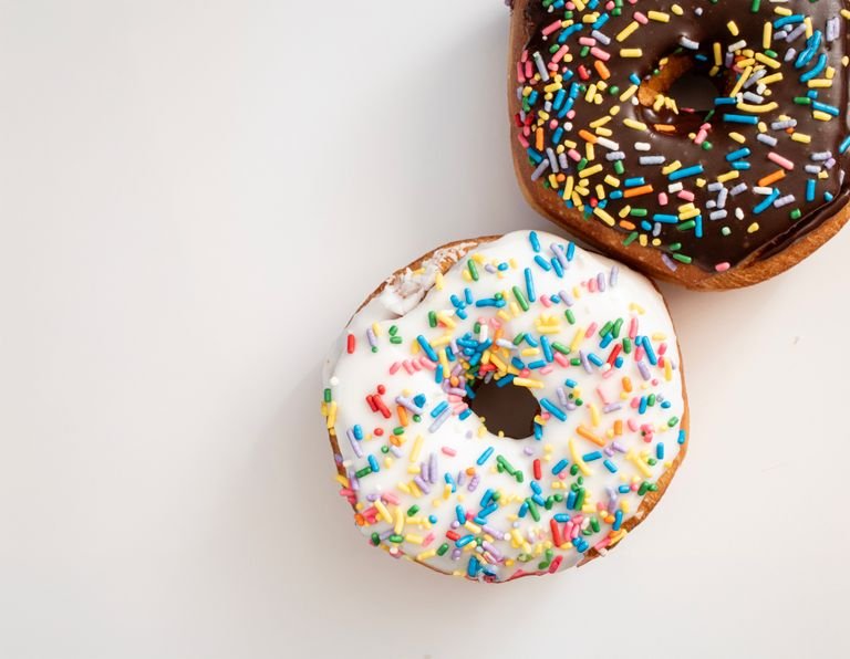 Two donuts with colorful sprinkles on a white surface, one with chocolate glaze - portillos donut calories 2026 nutrition guide